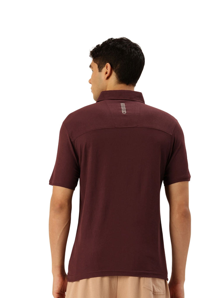 A man viewed from the back wearing a short-sleeve polo shirt in a deep burgundy color, paired with light beige pants, against a plain white background.