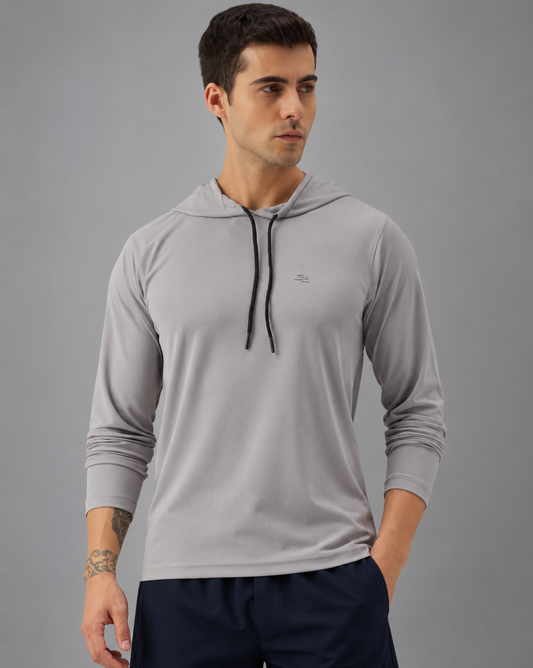 A man wearing a light gray long-sleeve athletic hoodie with black drawstrings, shown from the waist up against a plain greybackground.