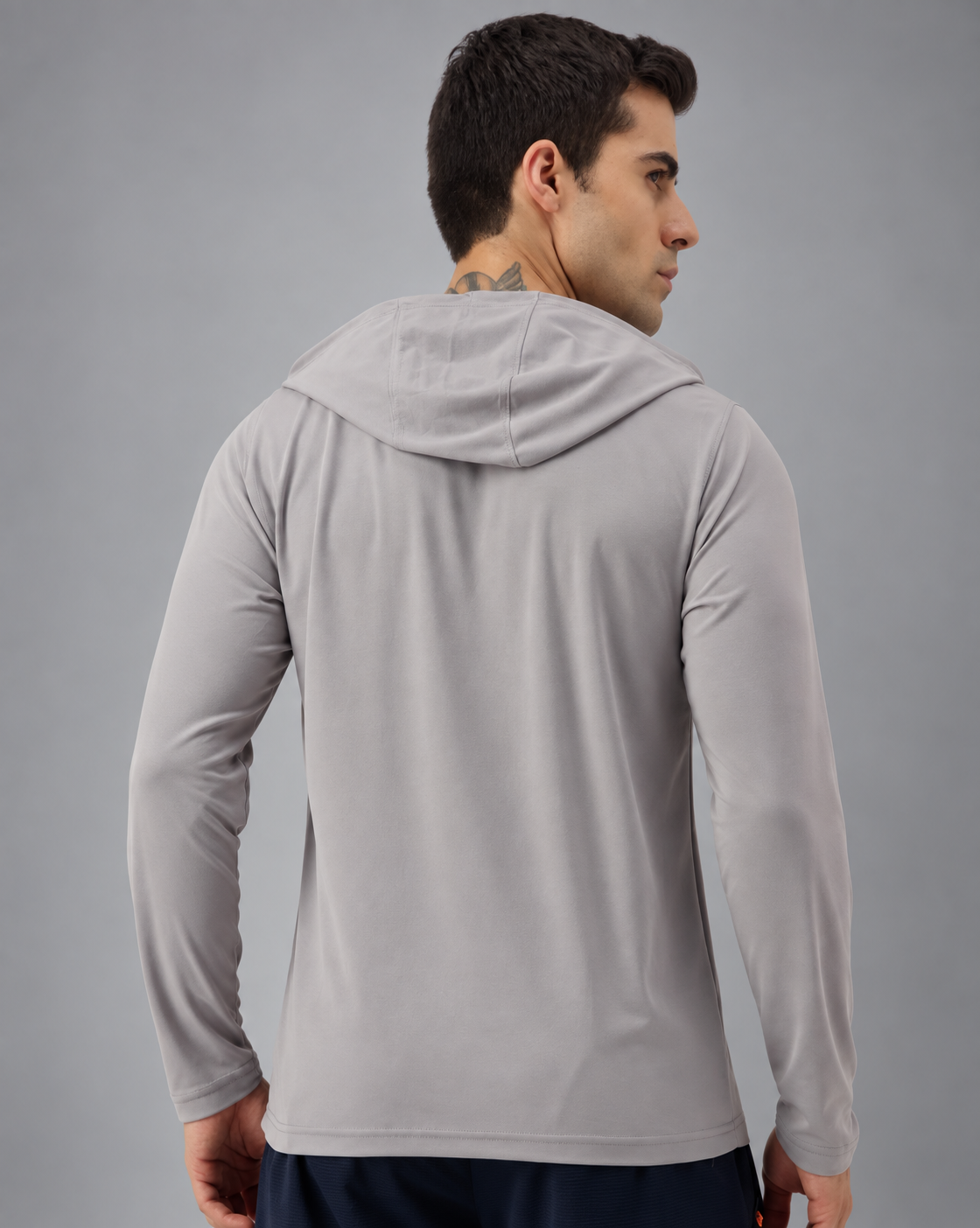 A man wearing a light gray long-sleeve athletic hoodie, shown from the back and side profile against a solid gray studio background.
