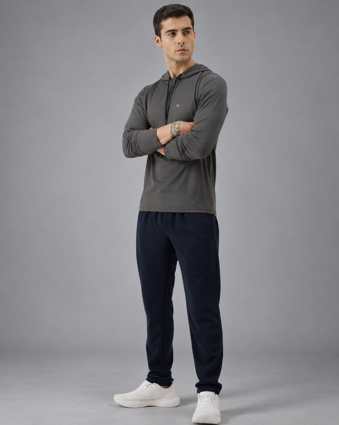 A man wearing a dark gray long-sleeve athletic hoodie with a small white chest logo, photographed against a solid grey background.