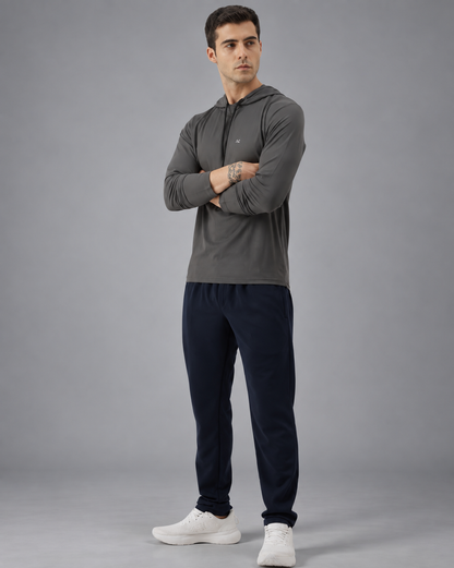 A man wearing a dark gray long-sleeve athletic hoodie with a small white chest logo, photographed against a solid grey background.